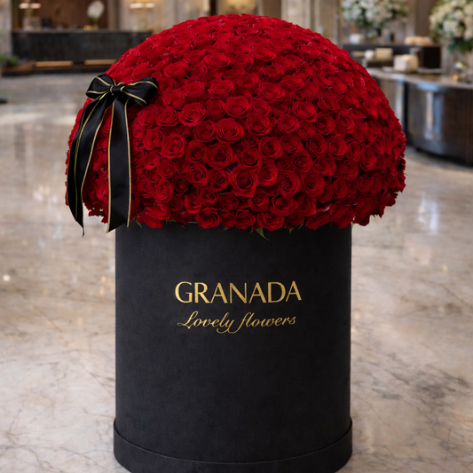 Black box with red roses and a bow, labeled 'GRANADA Lovely flowers', in an elegant interior setting.