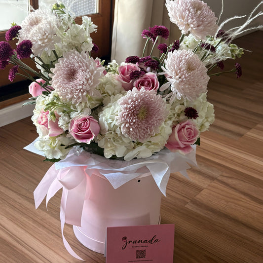 Bouquet of flowers on a wooden surface with a pink box labeled 'Givaudan'.