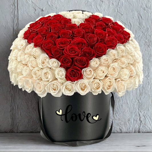 Heart-shaped arrangement of red and white roses in a black container with 'love' text on a gray background