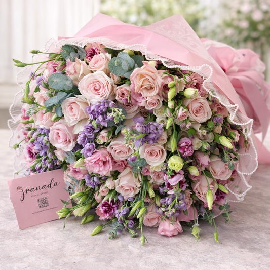 Bouquet of pink and purple flowers with a pink ribbon on a light surface, branded 'Jardnada'.