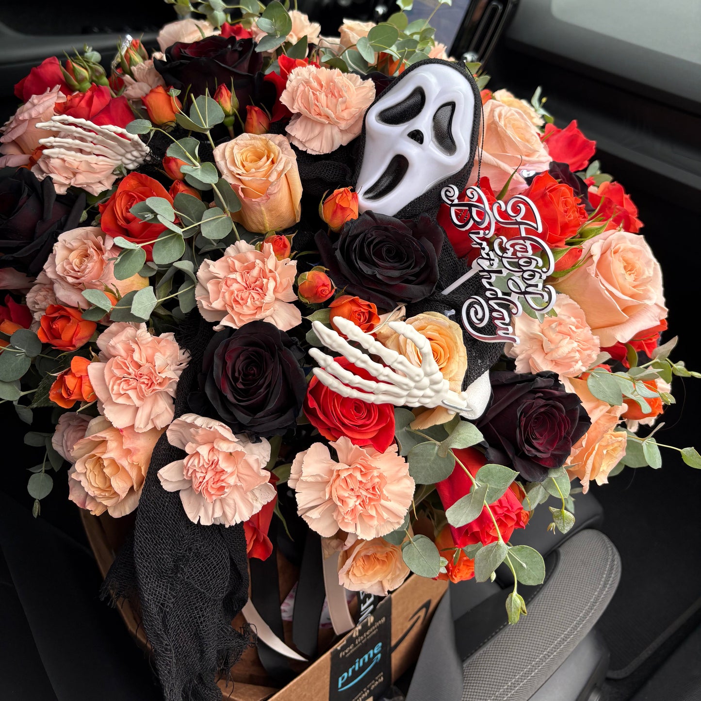 Bouquet of flowers with 'Happy Birthday' sign in a car's open door.