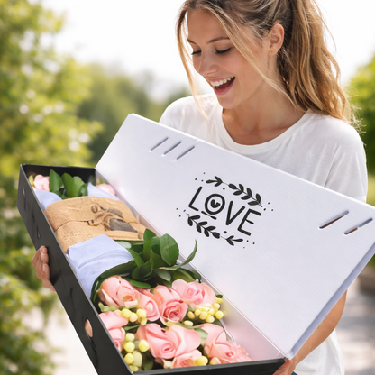 Woman holding a box with flowers and 'LOVE' text, outdoors.