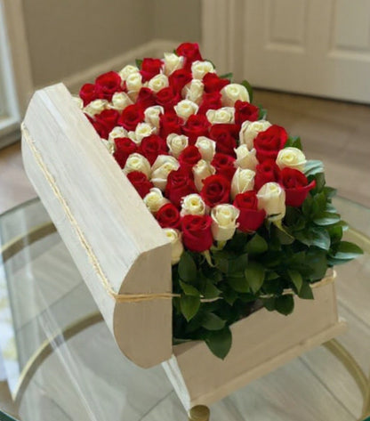 Arrangement of red and white roses on a glass table with a neutral background