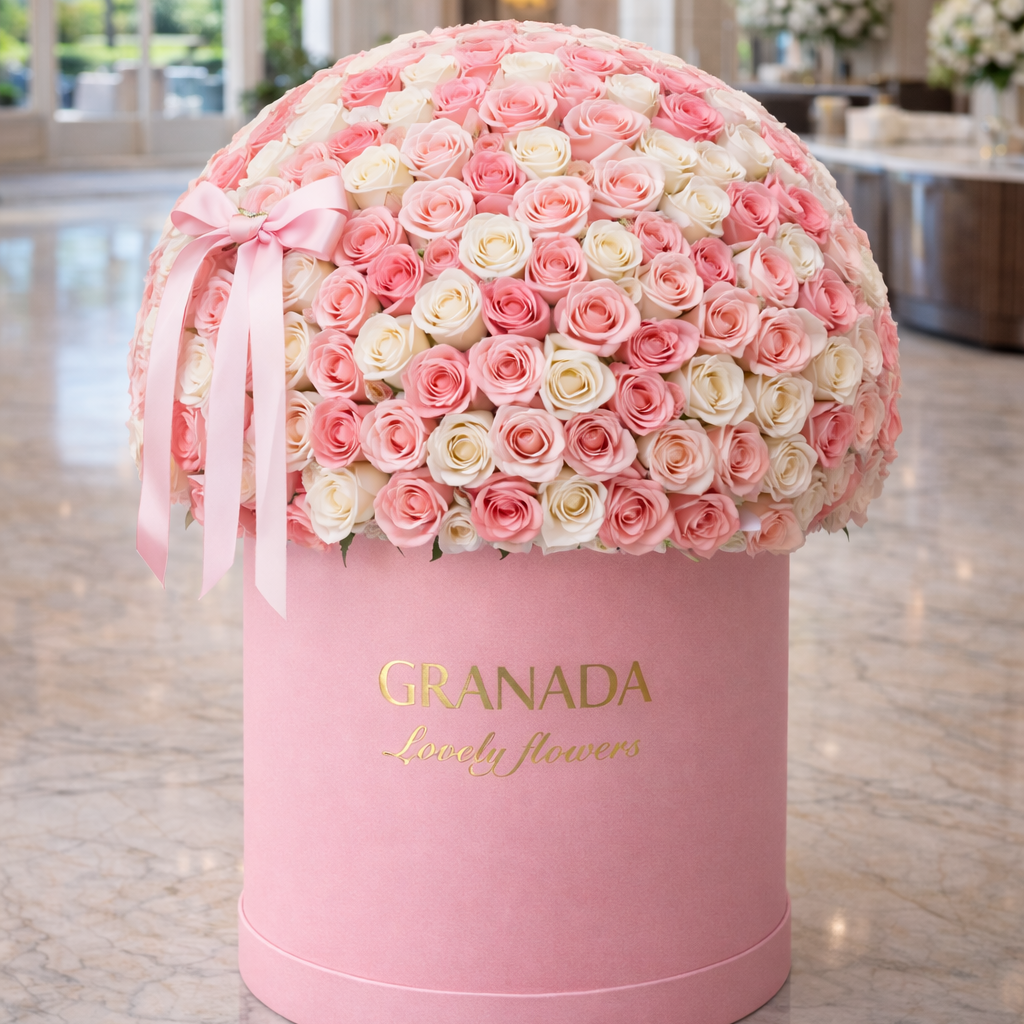 Pink and white flower arrangement in a decorative box with 'GRANADA' branding in a luxurious interior setting.