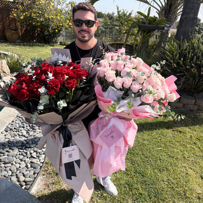 Man holding two bouquets of flowers outdoors with palm trees in the background
