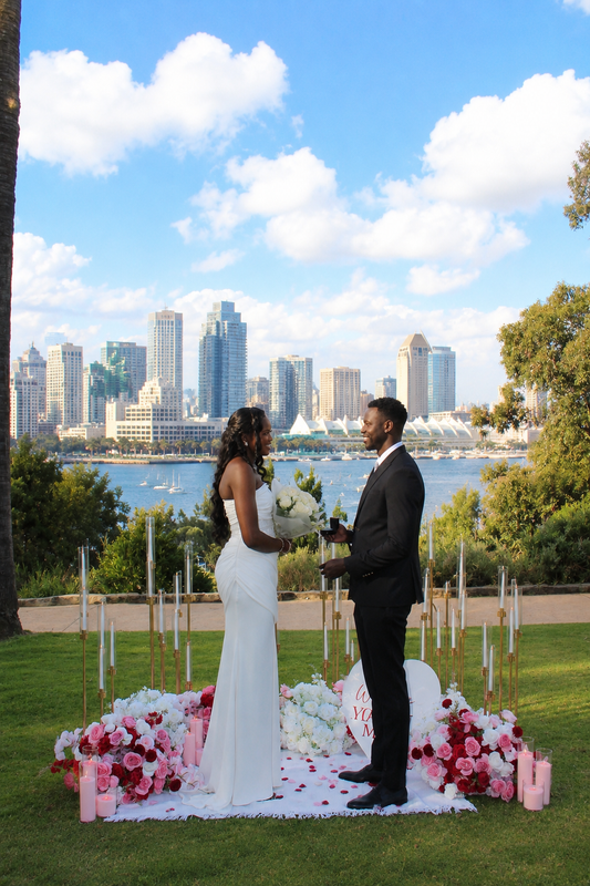 Romantic proposal moment with floral arrangement, candles and San Diego downtown skyline – Granada Floral Design