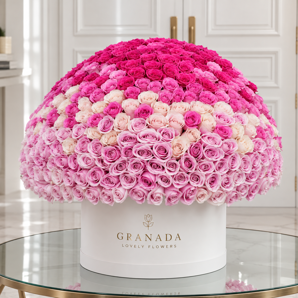Ombré rose dome arrangement with gradient from fuchsia to blush pink roses in white Granada hatbox on glass table
