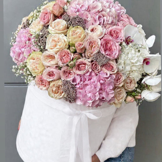 Bouquet of pink, white, and multicolored flowers held by a person wearing a white shirt.