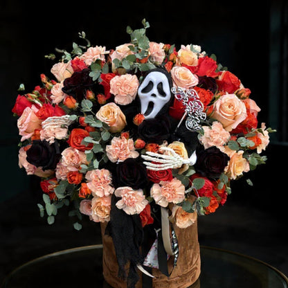 Decorative skull with floral arrangement and Halloween-themed props on a dark background