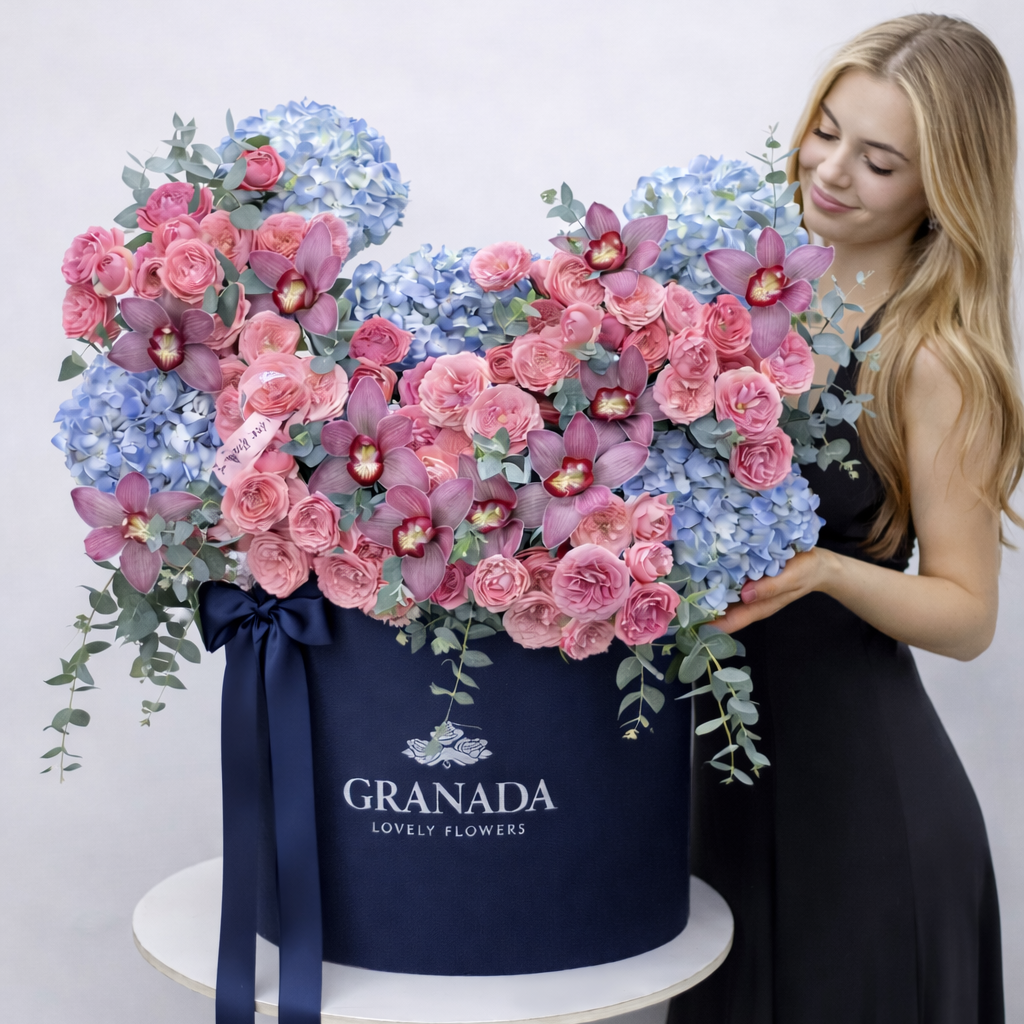 Woman holding a large bouquet of flowers in a 'Granada Lovely Flowers' box.