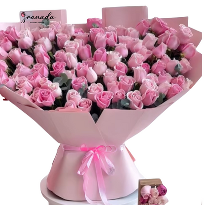 Bouquet of pink roses wrapped in pink paper with a bow, on a white background.