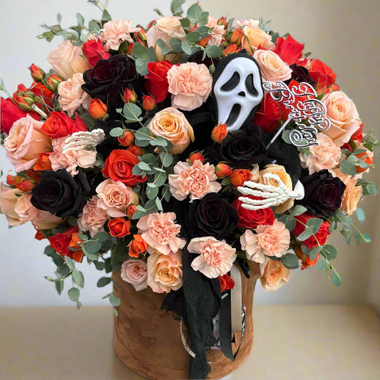 Halloween-themed floral arrangement with a ghost face mask and skeleton hand in a vase.