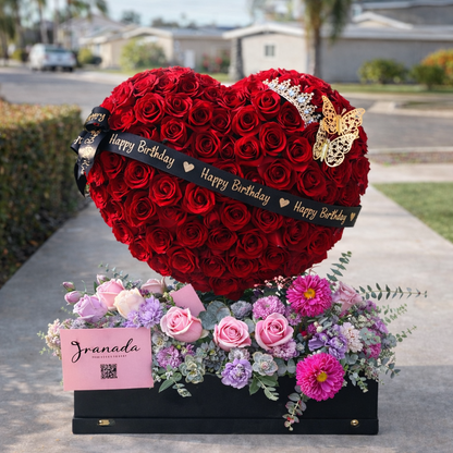 Heart-shaped arrangement of red roses with a 'Happy Birthday' ribbon and decorative butterflies, placed on a sidewalk.