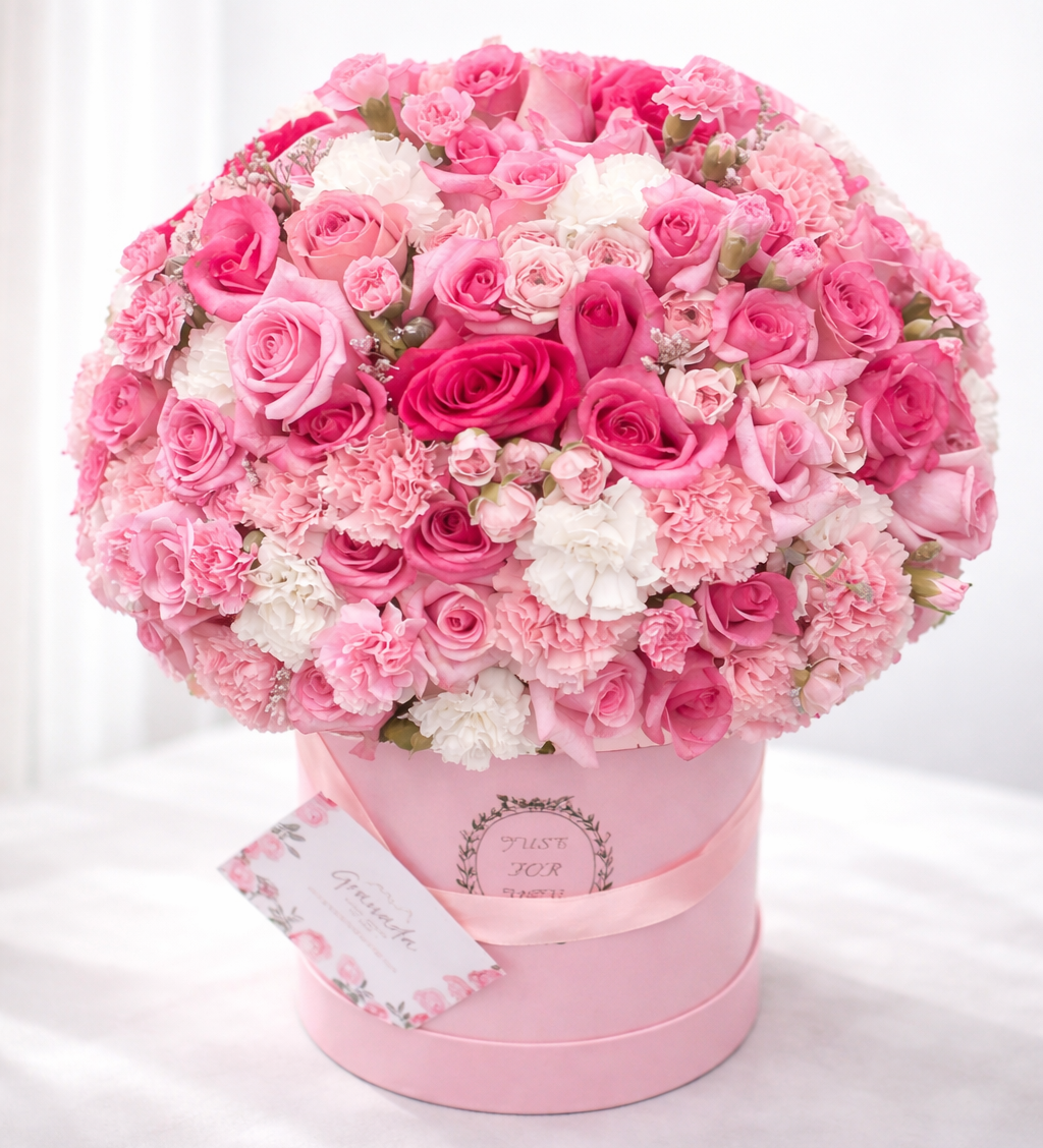 Pink and white flower arrangement in a pink box on a white background