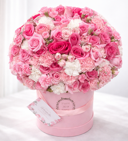 Pink and white flower arrangement in a pink box on a white background