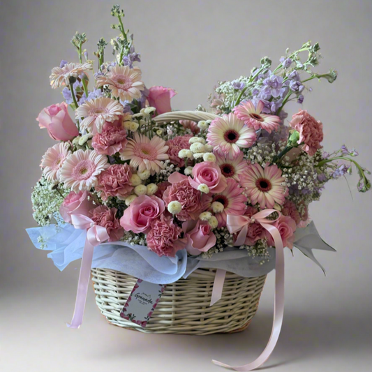 Floral arrangement in a basket with pink and white flowers on a light gray background